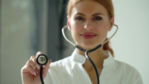 Gros plan de la femme médecin en blouse blanche à la clinique sur le lieu de travail tient stéthoscope dans sa main et écoute la respiration du patient potentiel. Femme médecin utilise stéthoscope — Video