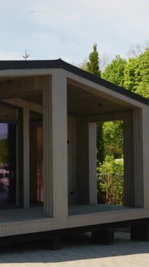 Tahta prefabrik küçük ev yavaşça dönüyor, geniş pencereli mimari ayrıntıları ortaya çıkarıyor, entegre güverte, modern sürdürülebilir yaşam tasarımı konseptini sergiliyor