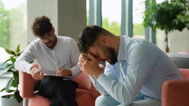 Profesyonel psikolog terapi seansı sırasında dikkatlice dinleyip notlar yazıyor. Duygusal zorluklarla ve zihinsel sağlık sorunlarıyla boğuşan hastaları şefkatle destekliyor.