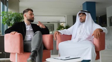 İki işadamı, biri batılı takım elbiseli, diğeri de geleneksel Arap kıyafetli, bir tartışmaya girişirler, bir belgeyi incelerler ve sonunda bir el sıkışma ile anlaşmayı imzalarlar.