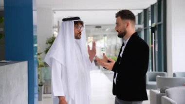 Çeşitli geçmişlerden şirket ortakları el sıkışıyor, çağdaş ofiste önemli bir anlaşma imzalıyor, küresel işbirliğini ve karşılıklı saygıyı simgeliyor