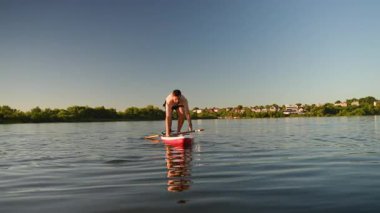 Deneyimli raketçi ayağa kalkar göl çalışması sırasında dengesini kaybeder, yaz güneşi altında kürek çekmeye yüzmeden önce beklenmedik bir şekilde suya düşer.