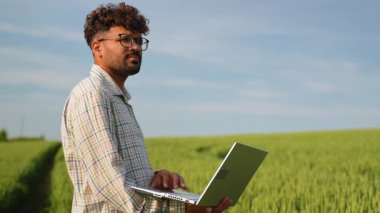 Modern tarım, bir çiftçinin geniş bir buğday tarlasında dizüstü bilgisayar kullanması ve dijital aletlerin tarım uygulamalarında entegrasyonunu sergilemesi gibi teknolojiyi kucaklıyor.