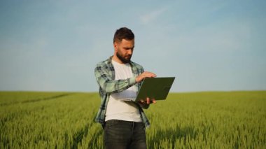 Modern tarım uygulamaları bir çiftçinin buğday tarlasında dizüstü bilgisayar kullanmasını, ekin büyümesini izlemesini ve tarım işlemlerini dijital olarak yönetmesini içerir.