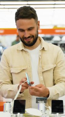 Modern elektronik mağazasında son teknoloji akıllı telefon işlevlerini araştıran tatmin olmuş müşteri, belli bir heyecan ile yenilikçi mobil teknoloji deneyimliyor