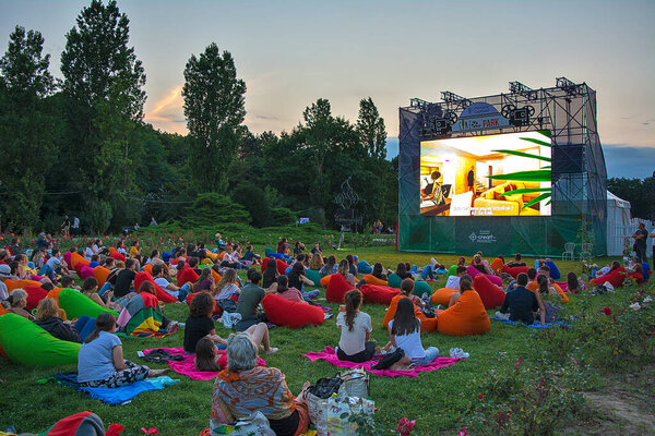 02 August 2018-Bucharest, Romania. People waiting and watching in the public park Herastrau for the movie to start on the projection screen of the open air cinema