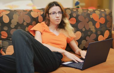 Evde dizüstü bilgisayarla çalışan sarışın, çekici bir kadın.