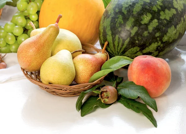 Sweet, juicy pear in wicker basket and another fruits on table