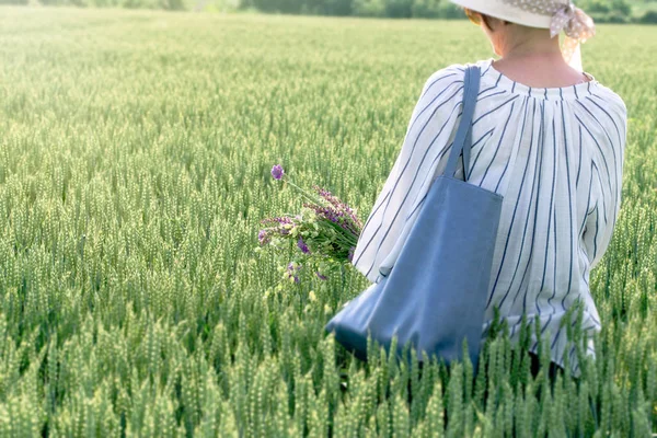 草原の花を手にした小麦畑の女性 — ストック写真