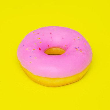 Sarı arka planda pembe çörek. Minimal yaratıcı gıda sanatı