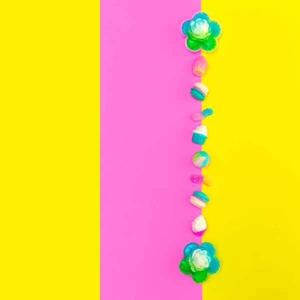 Makronen und Bonbons mischen sich auf farbigem Hintergrund. stilvolle flache Verlegung — Stockfoto