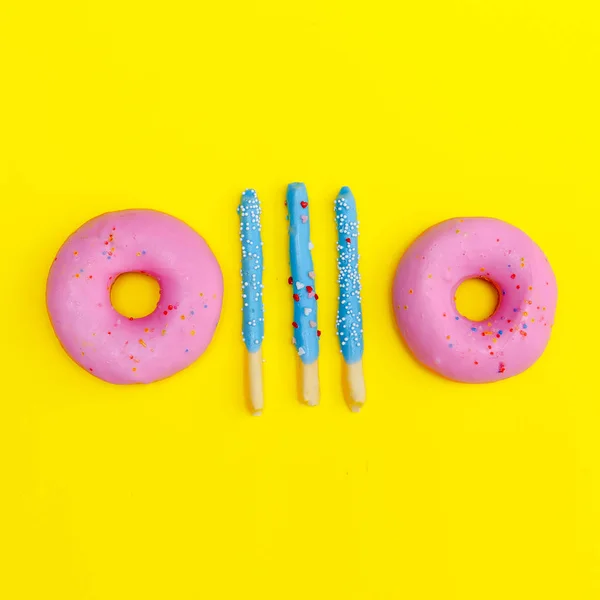 Donut y palitos dulces sobre fondo amarillo. Plano laico comida arte — Foto de Stock