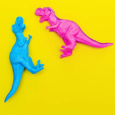  Renkli bir arka plan üzerinde Iki Oyuncak dinozorlar. Düz yatıyordu minimal ar