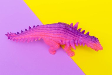 Renkli arka planda moda dinozor oyuncak. Minimal düz döşeme sanatı