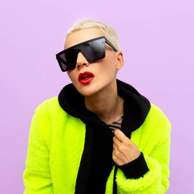 Kısa saçlı ve son moda güneş gözlüklü şık sarışın manken.