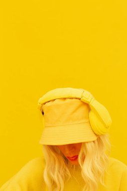 Hipster DJ Kız stüdyoda poz veriyor. Şehir tarzı. Hip-hop, dansçı. Moda kıyafetleri. Kova şapka. Sarı monokrom estetik renkler..