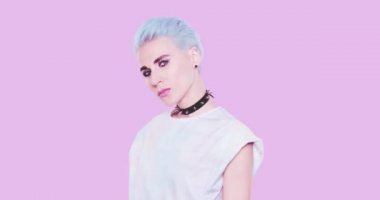Moda Estetik Alternatif Kadın, mavi kısa saçlı, stüdyoda mavi arka planda poz veren şık bir kadın. Modaya uygun duygular, saç stili ve aksesuar konsepti