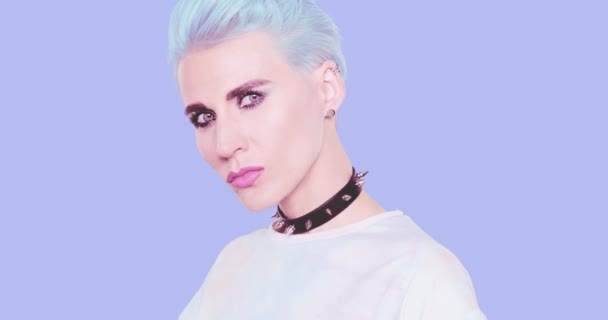 Ästhetische Alternative Mädchen mit blauen kurzen Haaren und stylischer Sonnenbrille posiert im Studio vor blauem Hintergrund. Mode-Emotionen, Frisur und Accessoires-Konzept — Stockvideo