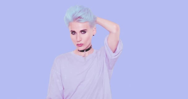 Menina alternativa sexy com cabelo curto azul e aparência casual elegante posando em estúdio contra fundo azul. Emoções de moda, penteado e acessórios conceito — Vídeo de Stock
