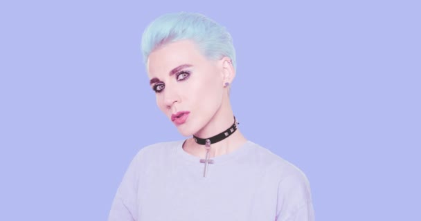 파란색 머리에 화려 한 평상복을 입고 푸른 배경을 배경으로 스튜디오에서 포즈를 취하는 패션 섹시 한 여성. 패션 헤어 스타일과 액세서리 개념 — 비디오