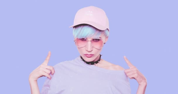 Chica alternativa de moda con cabello azul, gafas de sol elegantes y gorra posando en el estudio sobre fondo azul. Aspecto elegante urbano y concepto de accesorios — Vídeos de Stock