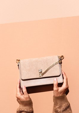 Kadın Elleri bej arka planda kadife debriyajı tutuyor. Uzayı kopyala Aksesuar moda konsepti, sonbahar kış sezonu. Bej rengi, kahverengi, sıcak hava. Şık, güçlü gölge tasarımı