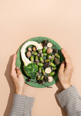 Eller bej tasarım arka planında sonbahar plakasını tutuyor. Üst Manzara. Sonbahar minimalist konsepti, Sonbahar kompozisyonu. Sonbahar akşam yemeği havası