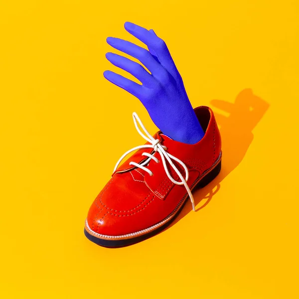 Fake hand and vintage shoes on yellow background. Fashion still life isometric art