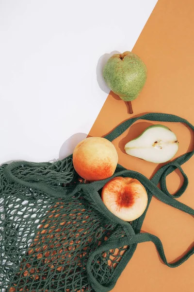 新鲜的桃子和梨子在网袋或绳袋中 零浪费 生态生活概念 平躺在床上最低限度 — 图库照片