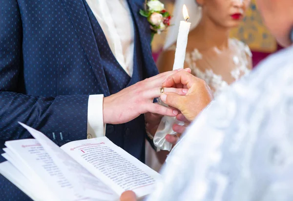 Les jeunes mariés se tiennent devant le prêtre lors d'une cérémonie de mariage et échangent les alliances — Photo