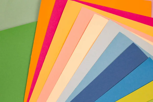 Färgade pappersark. Många färgade pappersark läggs ut i hårda sammansättning. bakgrund av färgat papper. — Stockfoto