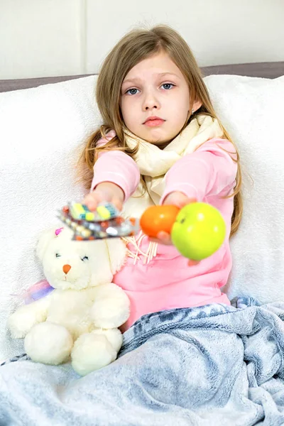 Una niña enferma toma medicamentos y come fruta. . — Foto de Stock