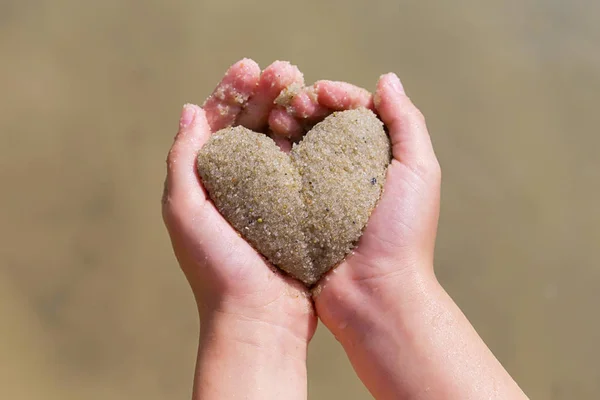 Les mains des enfants tiennent le cœur hors du sable, été, concept d'amour Images De Stock Libres De Droits