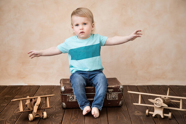 Happy child playing at home. Baby boy with toy airplanes. Summer vacation and travel, dream and imagination concept