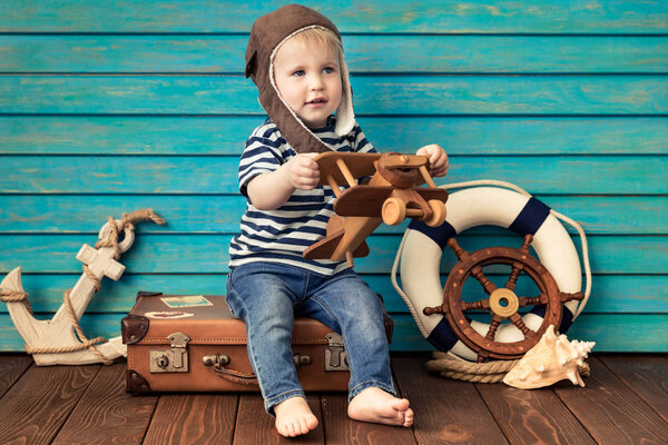 Happy child playing at home. Baby boy with toy airplane. Summer vacation and travel, dream and imagination concept