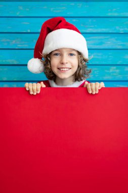 Karton afiş boş tutan komik çocuk. Evde oynayan çocuk. Noel tatil kavramı. Kopya alanı.