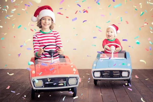 クリスマスの時に楽しい様子 家で一緒に遊んでいる子供 女の子と男の子のおもちゃの車に乗って — ストック写真