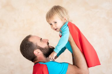 Adam ve çocuk süper kahraman evde. Süper kahraman baba ve oğul birlikte eğleniyor. Aile tatil kavramı. Mutlu babalar günü
