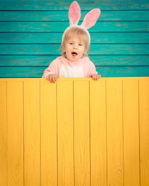 Paskalya bunny kostüm giyen ve ahşap tutan komik çocuk kurulu afiş.