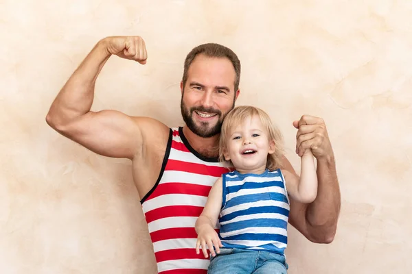 男子和幼儿儿子穿着条纹衬衫摆在家里 — 图库照片