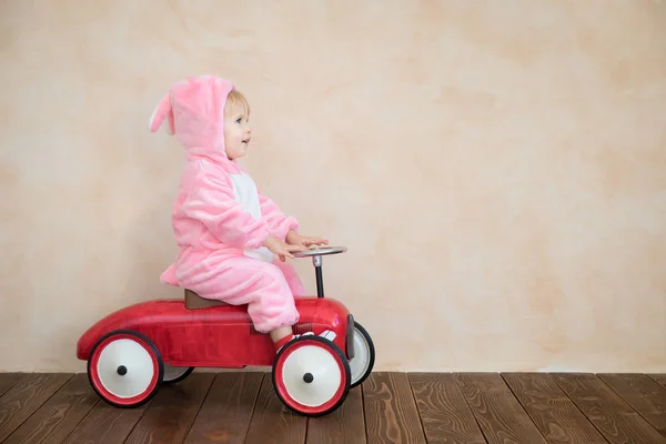 有趣的孩子穿着复活节兔子服装和骑玩具车在家里 — 图库照片