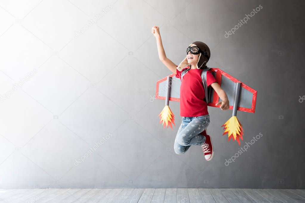Happy child playing with toy jetpack, studio shot.