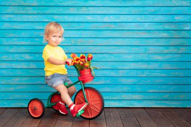 Funny child riding bike. Happy kid having fun at home. Spring family holiday concept. Mothers day
