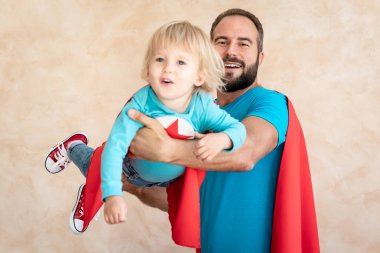 Adam ve çocuk süper kahraman evde. Süper kahraman baba ve oğul birlikte eğleniyor. Aile tatil kavramı. Mutlu babalar günü