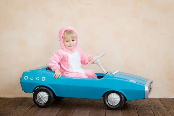 穿着复活节兔子的有趣的孩子孩子们在家骑玩具车 春假概念 — 图库照片