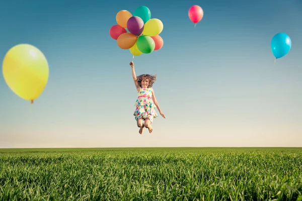 明るい多色の風船を屋外で遊んで幸せな子供 青い空を背景に緑の春のフィールドで楽しんでいる子供 健康で活動的なライフスタイルのコンセプト — ストック写真