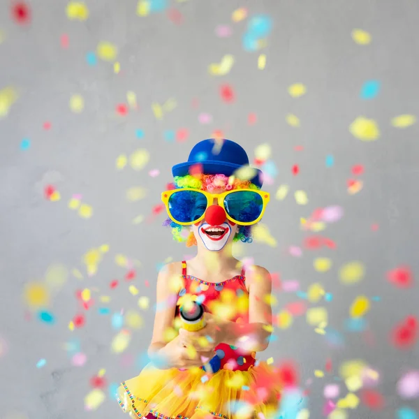 Funny kid clown with party poppers. Happy child playing at home. 1 April Fool\'s day concept