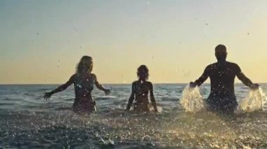Mutlu bir aile yaz tatile eğleniyor. Baba, anne ve denizde oynayan çocuk. Etkin sağlıklı yaşam konsepti
