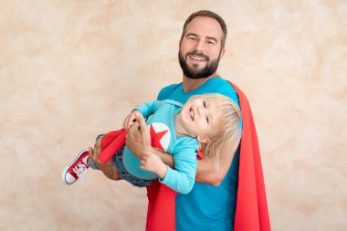 Adam ve çocuk süper kahraman evde. Süper kahraman baba ve oğul birlikte eğleniyor. Aile tatil kavramı. Mutlu babalar günü
