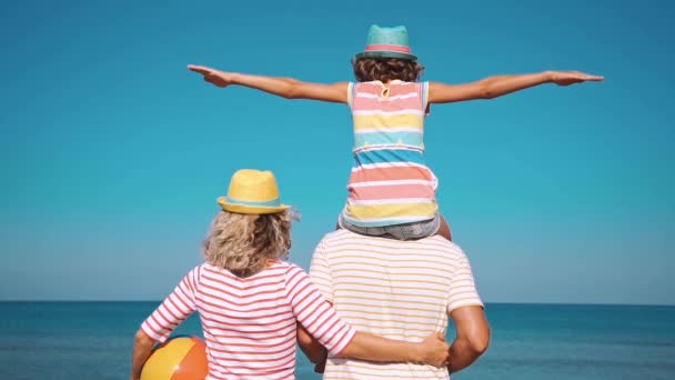 ビーチで幸せな家族 夏休みを楽しんでいる人たち 青い海と空を背景に父 休暇旅行のコンセプト — ストック動画